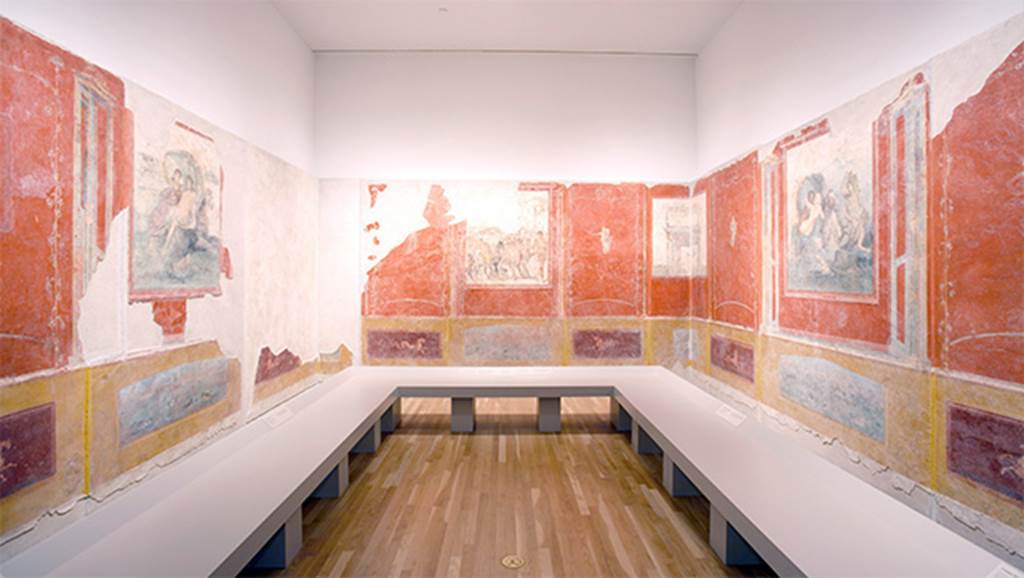 Gragnano, Villa rustica in Località Carmiano, Villa A. Triclinium 1. 
Reconstruction of room, looking south. 
The three walls had each a central panel with a fresco and side panels with female figures in flight. 
Architectonic perspectives which continued round the corners, suggested a unitary space removing the corners and giving continuity to the walls.
See Bonifacio G., 2004. In Stabiano: Exploring the Ancient Seaside Villas of the Roman Elite. Castellamare: Nicola Longobardi, p. 72.
