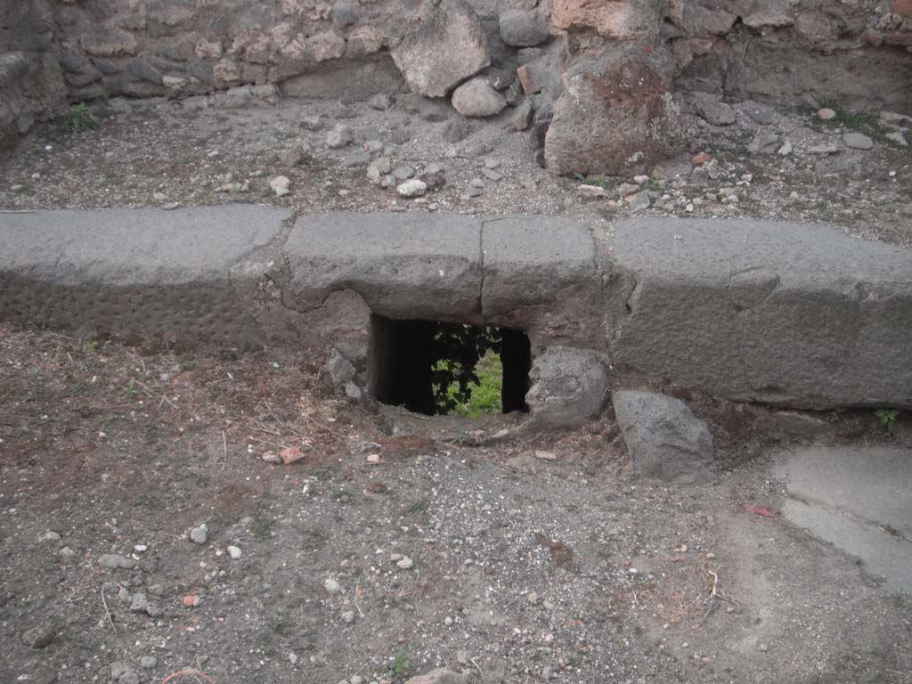 Vicolo dei Soprastanti, Pompeii. May 2011. Drain beneath the colonnade on north side of roadway. Photo courtesy of Ivo van der Graaff.
According to Van der Graaf –
“Only a single example exists of a drain passing through the curtain wall other than at the gates. It opened beneath the ornamental engaged colonnade that served to mark the edge of the fortifications and the natural cliff edge along the vicolo dei Soprastanti. The drain was slightly less in the public eye that the gates. Yet engineers formalized the water falling from the city into a cascade draining from the streets into a natural channel passing through the garden of the House of Maius Castricius (VII.16.17). In the course of the first century BCE, workers contained the channel into a series of shallow open-air clearing tanks designed to store and filter the water for reuse. The fortification wall above the formalized channel preserves the triangular peephole in the wall that offered a good view of the water works below. From here, viewers could observe the controlled outflow of water from the city.”
See Van der Graaf, I. (2018). The Fortifications of Pompeii and Ancient Italy. Routledge, (p.105 & Note 118 and 119).

